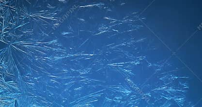 Blue winter background of ice crystals forming and frost freezing on window