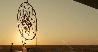 Native American dreamcatcher hanging in breeze at sunset.
