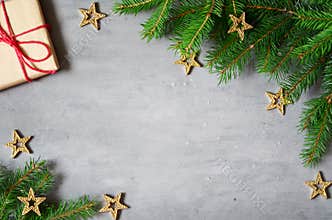 Christmas presents with red ribbon on gray background in a frame made of fir branches with star. Flat lay, top view. Christmas