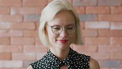 Smiling female in glasses over brick wall