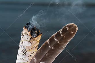 Smudging Ritual using burning thick leafy bundle of White Sage Grade A barred Turkey Smudging Feather on the beach at sunrise