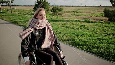 Smiling handicapped woman in wheelchair on enjoyable outdoor walk