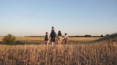 Children and father and mother with backpacks travel through the valley. Dad mom with daughters go camping. Family of