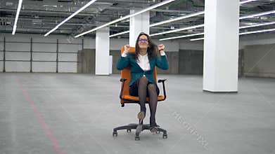 Female worker having fun, riding an office chair.