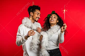 Young african american couple with christmas bengal sparklers isolated on red