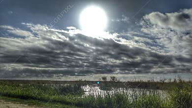 Sunshine through the clouds over swamp