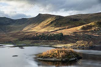 Stunning Autumn Fall landscape of Hawes Water with epic lighting and dramatic sunlight in Lake District