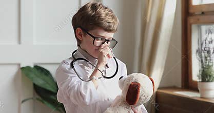Funny preschooler boy wear medical coat hold stethoscope listen toy