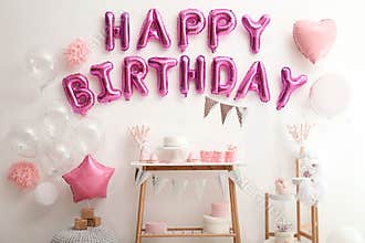 Phrase HAPPY BIRTHDAY made of balloon letters on white wall