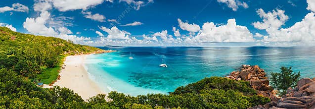 Aerial Pano of Grand Anse beach at La Digue island in Seychelles. White sandy beach with blue ocean lagoon and catamaran