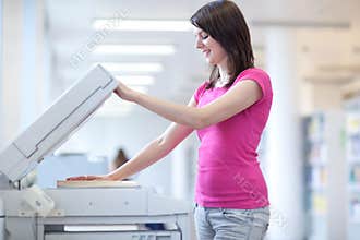 Pretty young woman using a copy machine