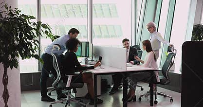 Multiethnic staff using computers talking in big office