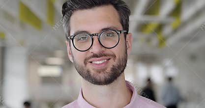 Close up of happy handsome man in glassess looking to camera and smiling. Bearded male office worker in good mood