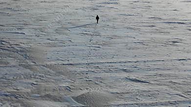 Aerial top view of a man with a backpack walking by the tundra.