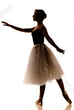 Silhouette of young beautiful ballerina in white tutu and pointe shoes doing dancing pose