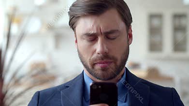 Serious business man reading bad news on phone. Disapointed man on sofa.