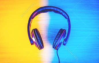 Black headphones on dark wooden background, In-ear headphones for playing games and listening to music tracks, Vintage style