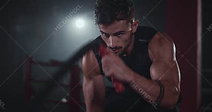 Portrait of sweeting athletic man doing exercises on the ropes in the cross fitness class he are concentrated on his