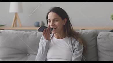 Happy millennial girl activating virtual assistant on mobile phone.