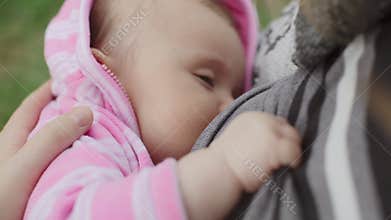 Young mother breast feeding her baby girl outdoors