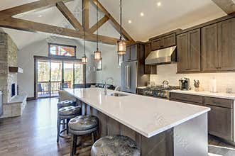 Amazing modern and rustic luxury kitchen with vaulted ceiling and wooden beams, long island with white quarts countertop