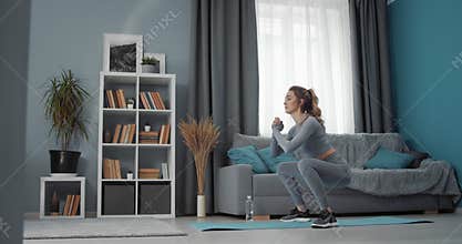 Sporty woman doing squats during workout at home