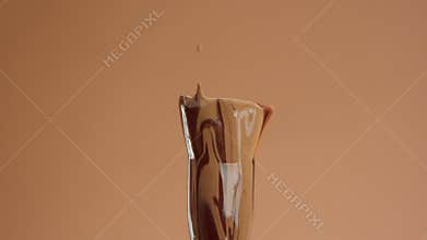 A foundation brush with a liquid foundation for deep skin tones covering it and falling