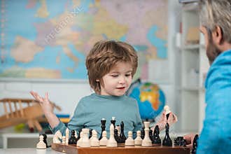 Happy child and childhood. Boy kid playing chess at home. Concentrated boy developing chess strategy, playing board game