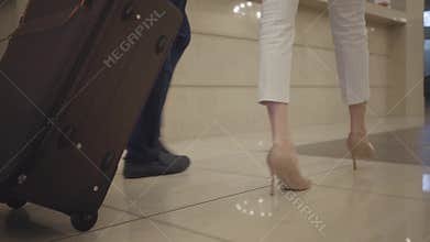 Camera following male and female Caucasian feet walking to hotel reception. Wealthy clients checking in. Rich man and