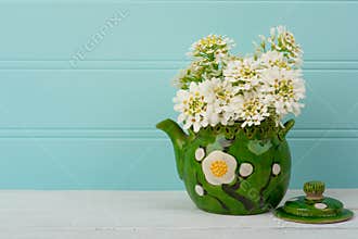 Pretty White Spring Flowers in a Vintage Asian Pot on Wood Table with Teal Boards Background in shabby chic style.  It`s a Horizo