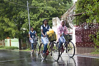 On a rainy day girls going to school on bicycles