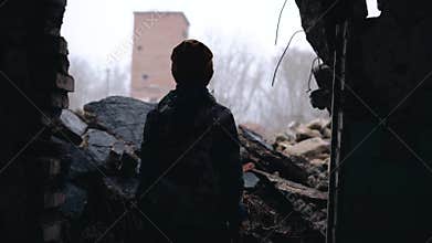 A teenager stands in the ruins of a house. Everything is destroyed