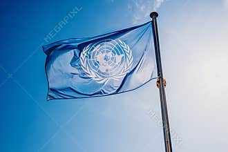 UN flag waved against the sun and blue sky