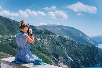 Adult female tourist with camera enjoying seascape of Kefalonia, Greece on summer holiday vacation