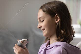 Loving teenage girl play with cite domesticated mouse at home
