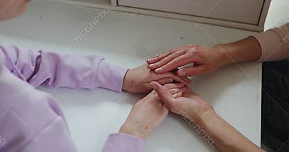 Close up view affectionate mother stroking hands of teen daughter.