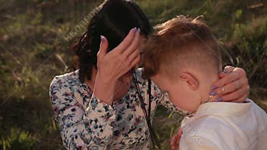 Cross necklace man`s neck. The mother puts on silver catholic symbol for her son