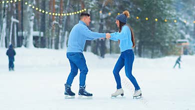 Guy in sweater tries to amaze girl on outdoor ice rink