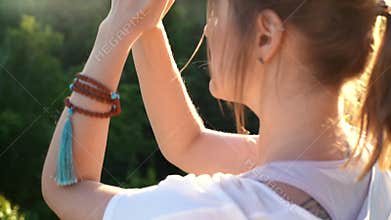 Tracking shot of meditative young woman sitting in lotus position raising hands in Namaste pose.