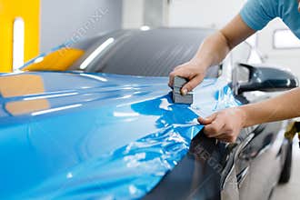 Car wrapping, mechanic with squeegee installs film