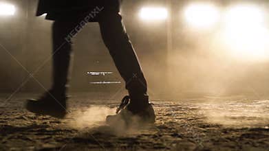Slow motion. Person`s foot steps in front of the camera and leaves dusty footprints. Close-up of confident walking along