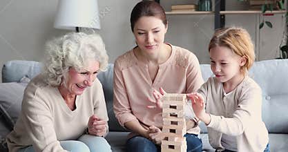 Happy granny and mommy supporting little child in build game.