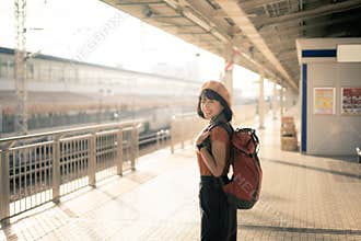 Young Asian woman traveller with backpack waiting for train at train station. A woman journey in Japan. Travel and lifestyle