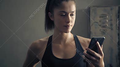 Woman using smart phone with personal trainer workout app at home. Woman preparing for workout using fitness app. Close