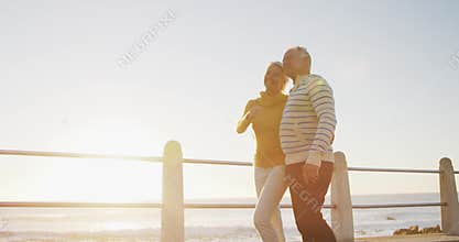 Senior couple walking alongside beach