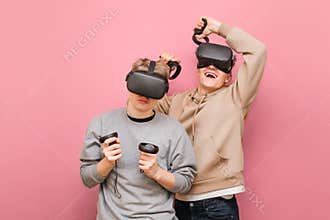 Two expressive friends in VR helmets compete in virtual reality games. Guy on the right is happy to win, another loser is upset by