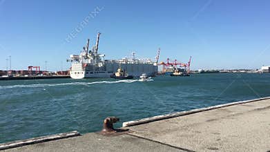 Tugboats pulling out from a dock a cargo ship in Fremantle Harbour WA