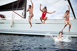 Friends jumping from sailboat on sea ocean trip