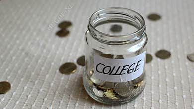 Coins filling and overflowing a clear medium sized glass jar