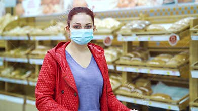 Woman in mask standing in bakery against shelves with bread